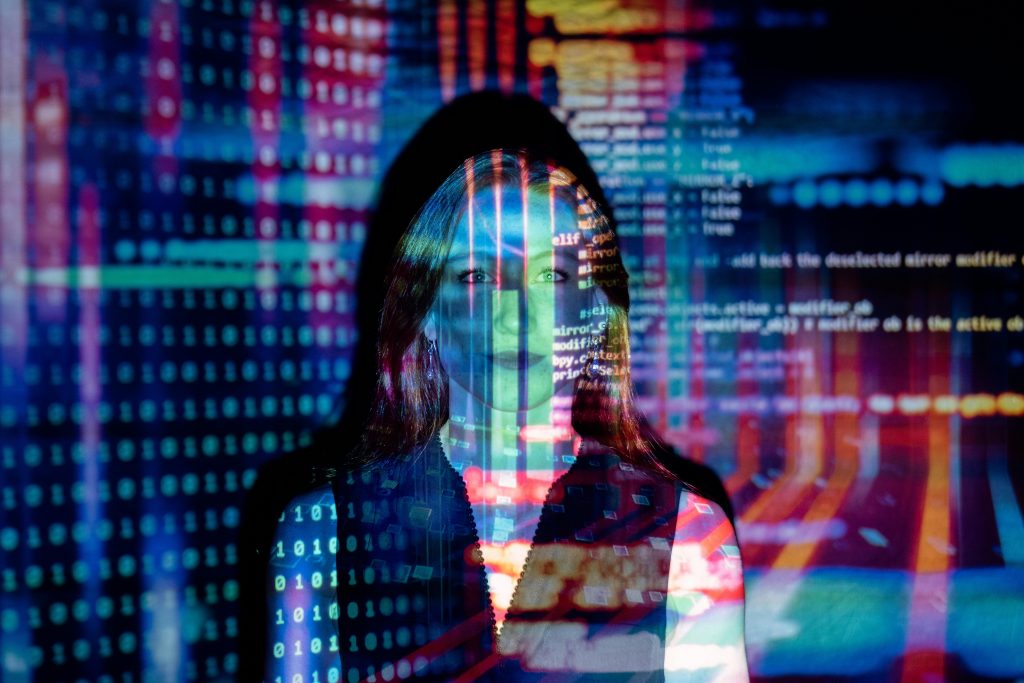 Woman's face with projected images of typed code and binary code overlapping on her face